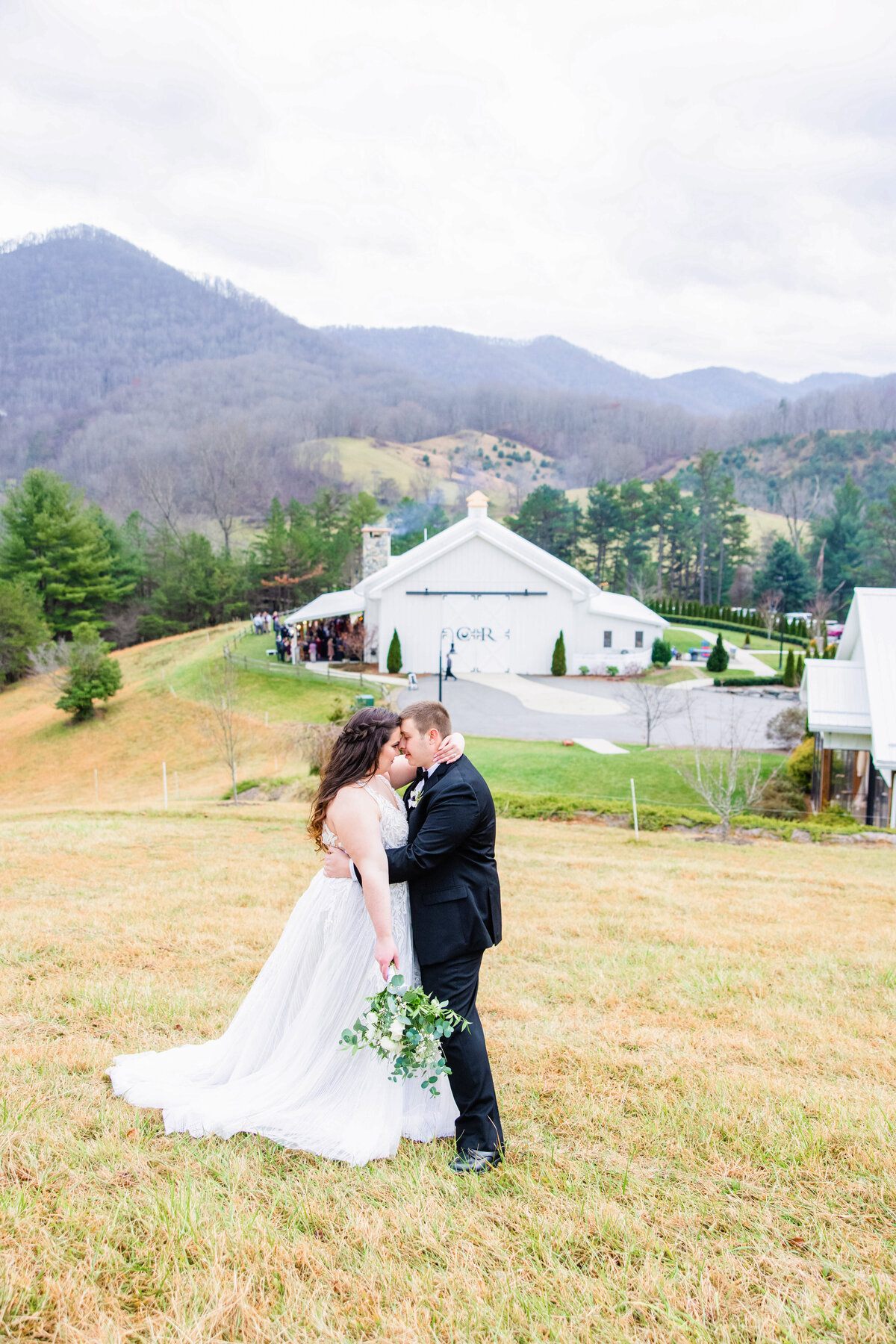 bride and groom forehead to forehead on wedding day with barn in the background