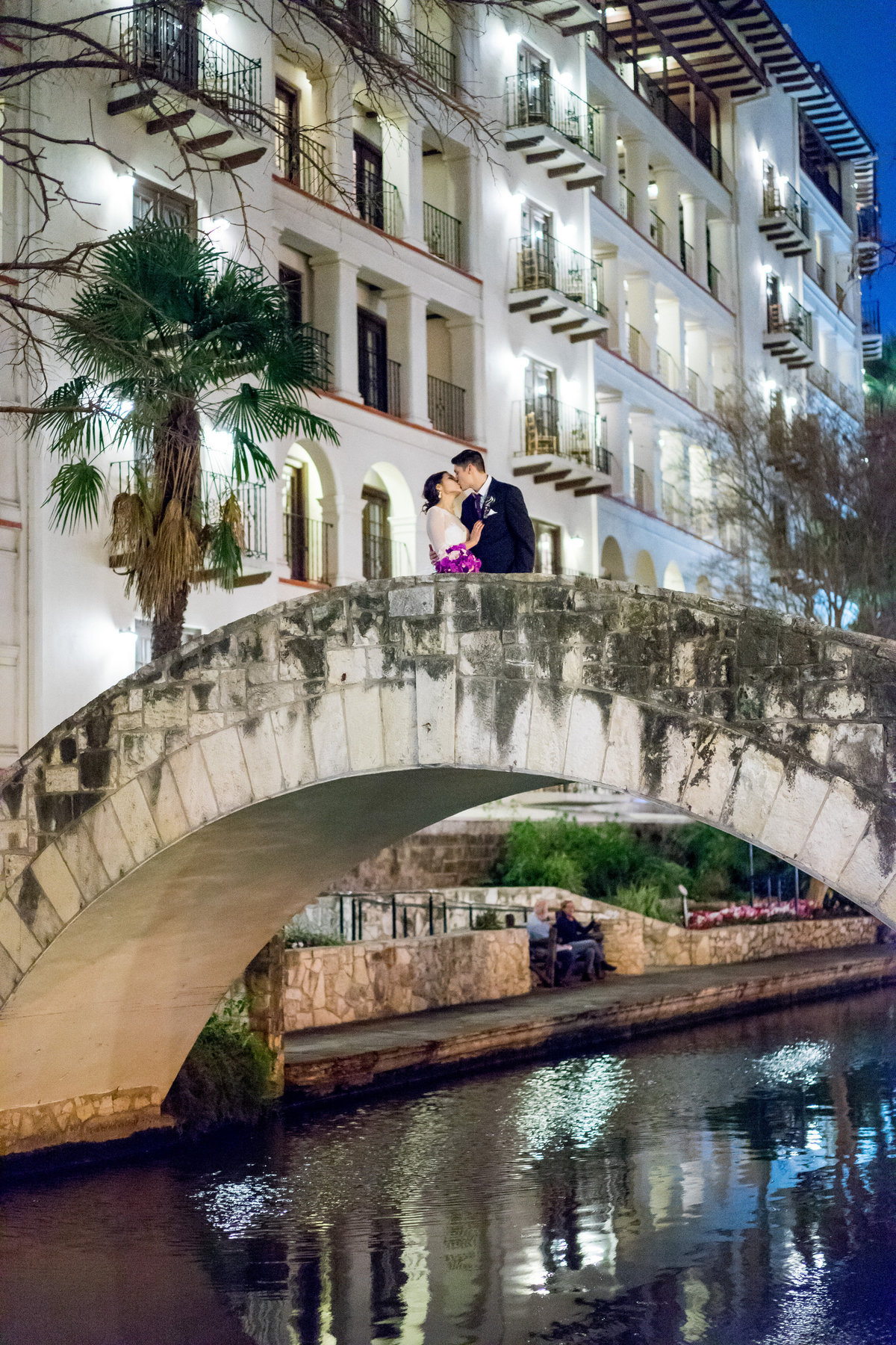 Groom kissing his bride on a stone bridge at Omni La Mansión del Rio on San Antonio Riverwalk by Wedding photographer