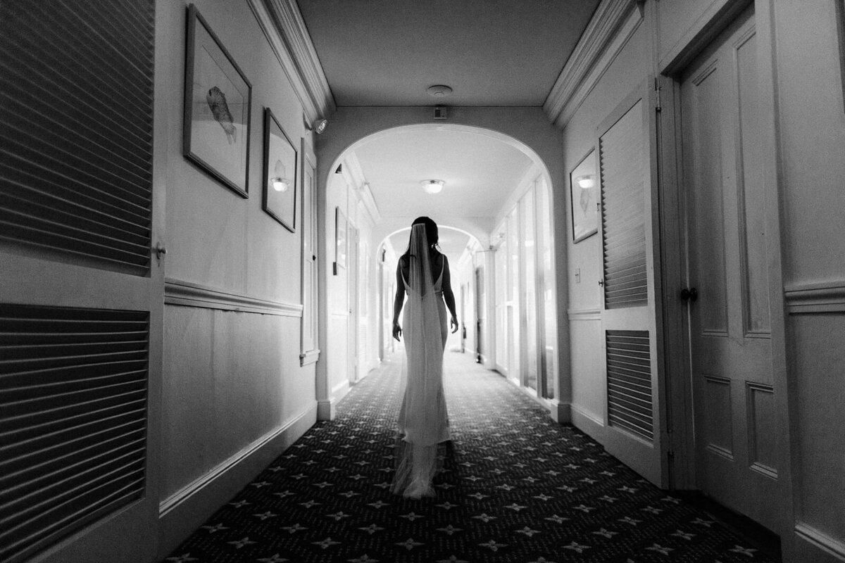 Black and white, back view of the bride standing in a hallway, at Wianno Club, Cape Cod, MA.
