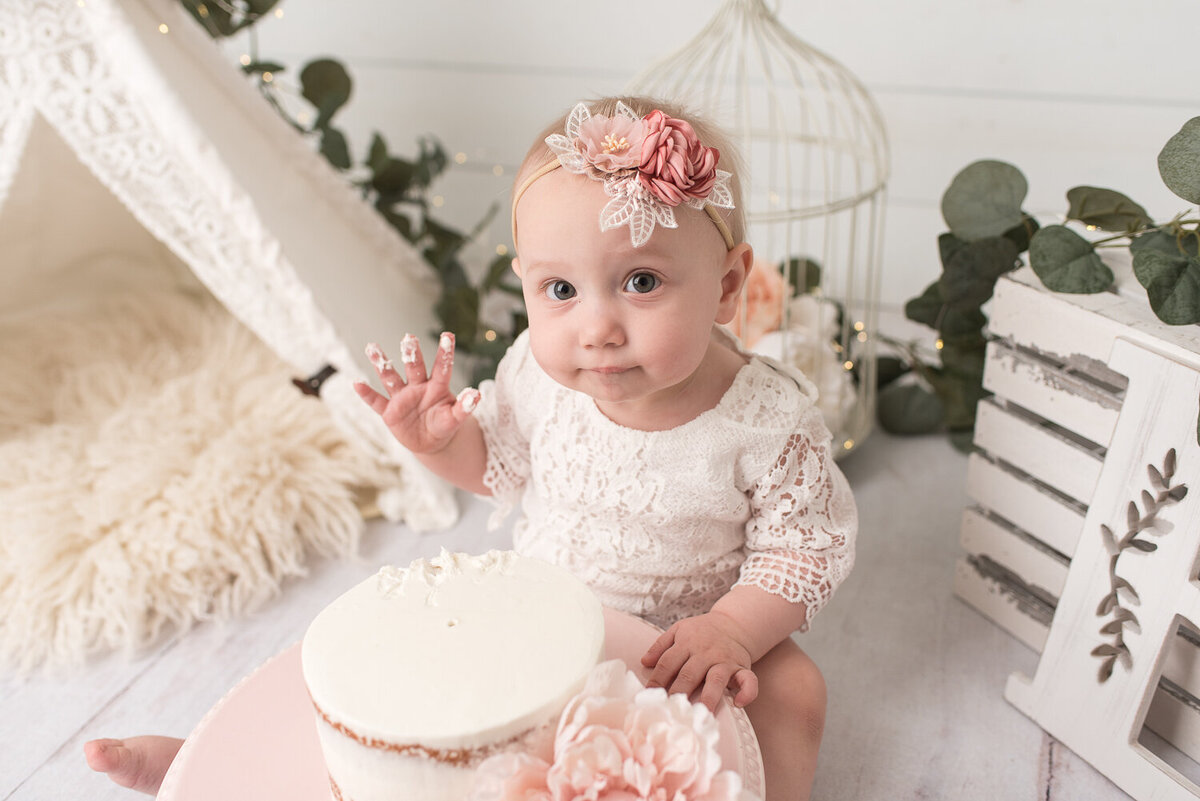 One year old girl looking at camera while eating first birthday cake |Sharon Leger Photography || Canton, CT || Family & Newborn Photographer