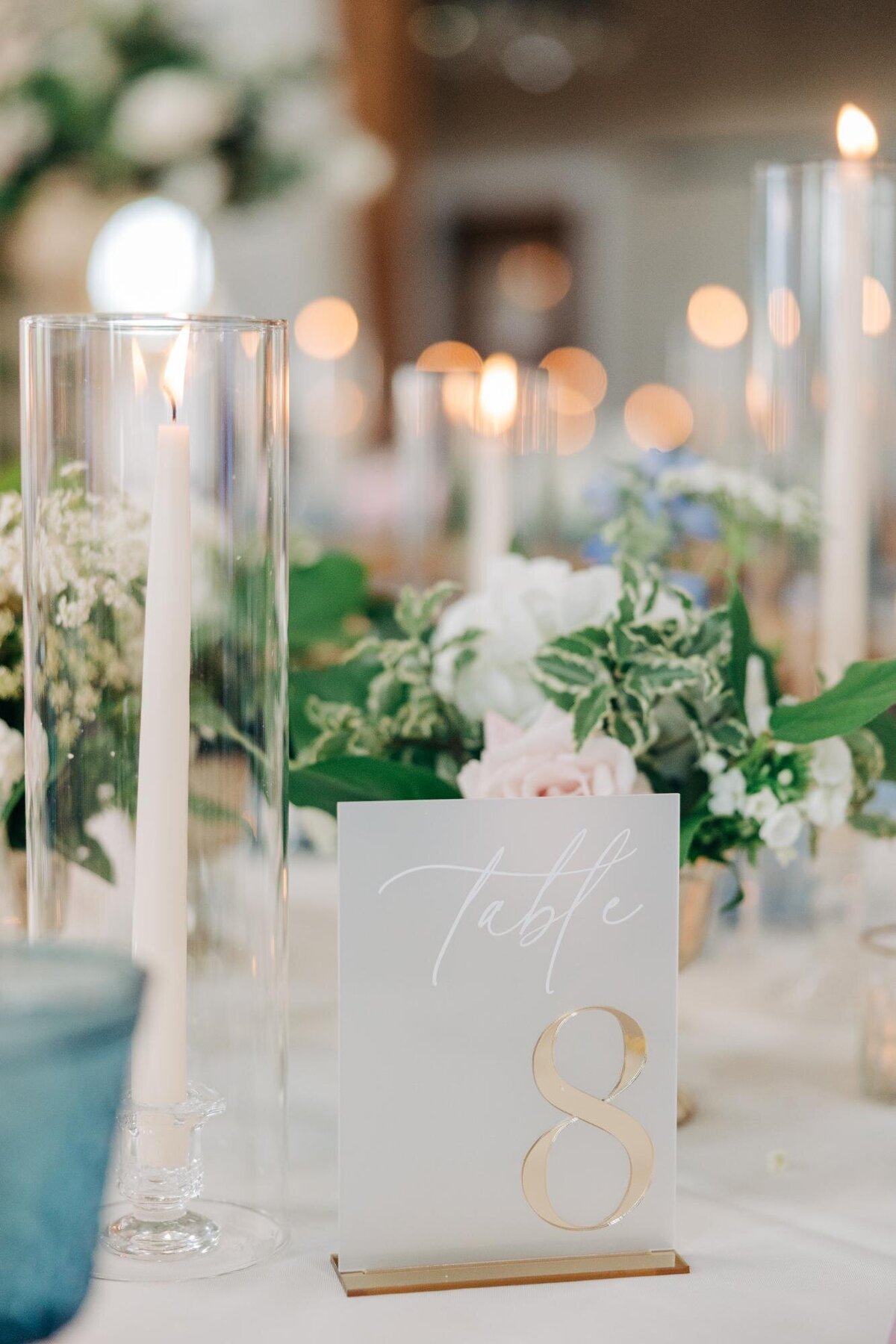 Elegant wedding table setting with a number 8 sign, candles, and floral arrangements.