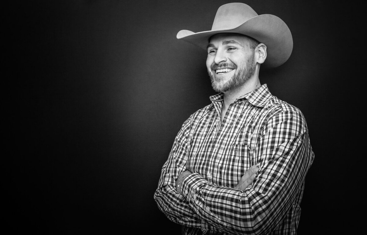 Studio portrait of a man wearing a cowboy hat standing under cinematic lighting, exuding an editorial vibe.