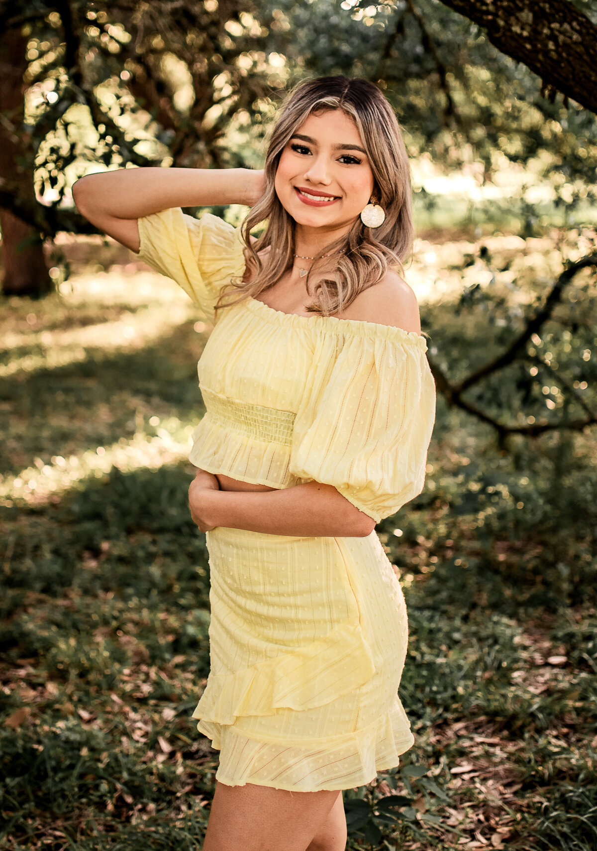 A girl wearing yellow poses for her senior pictures at Memorial Park.