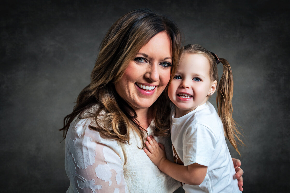 Mother and daughter embrace against a dappled gray traditional studio background in Pittsburgh Pennsylvania