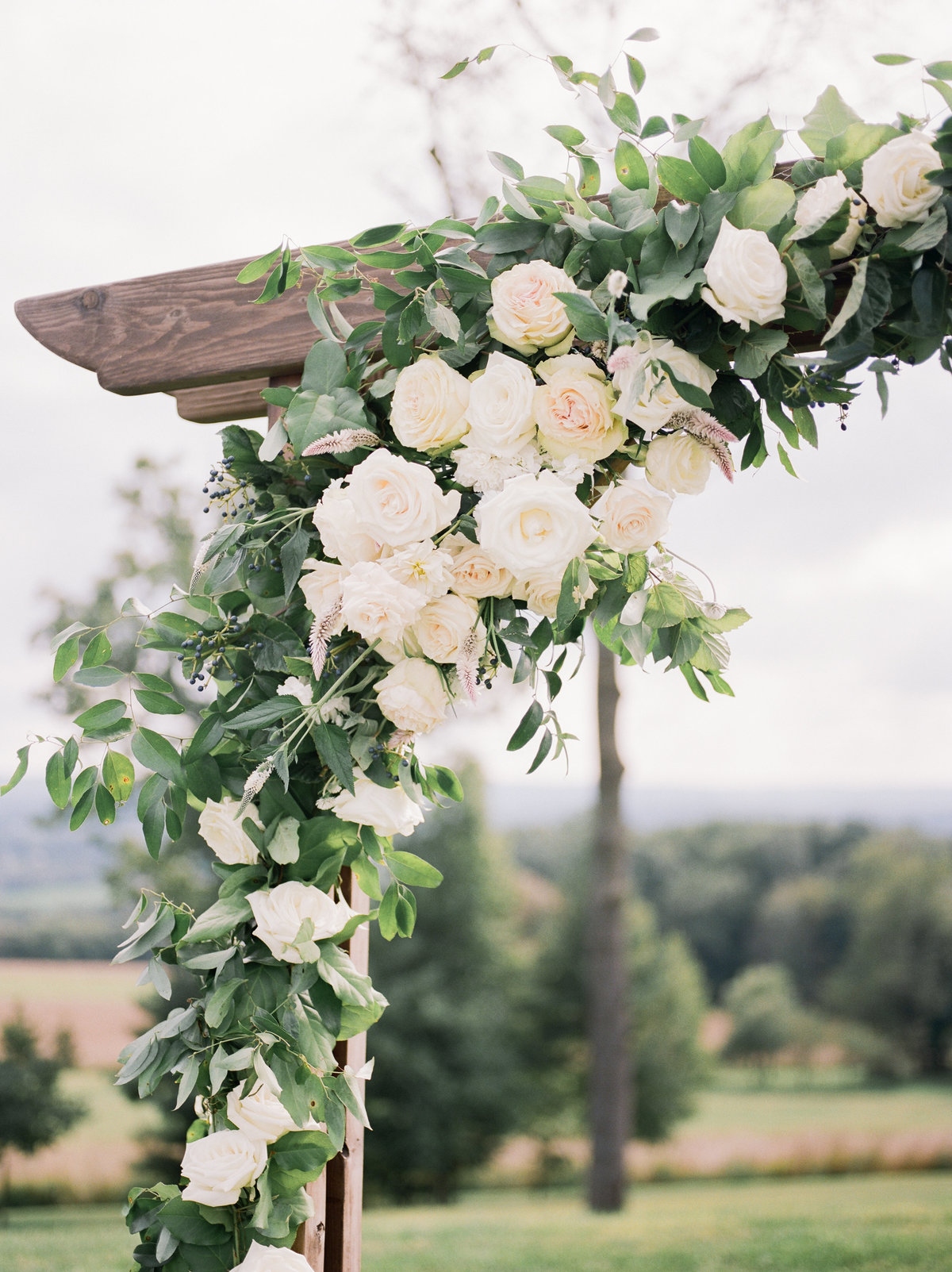 wooden wedding alter with white roses and greenery