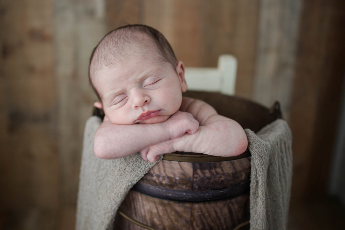 Newborn baby boy sleeping in a bucket