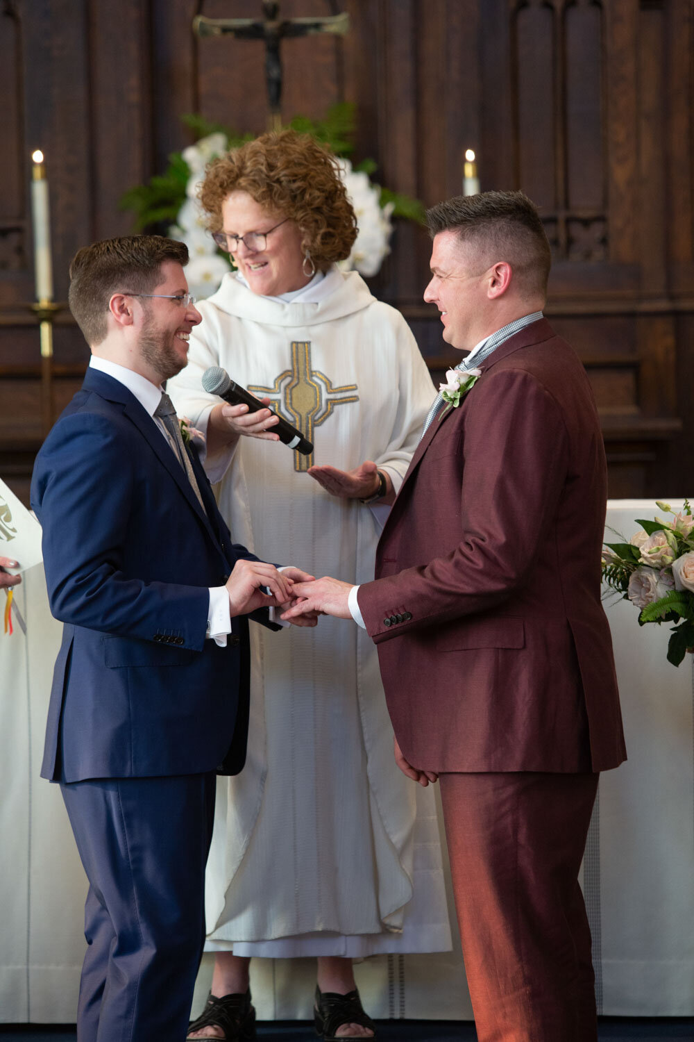 Two men in suits are getting married in a church