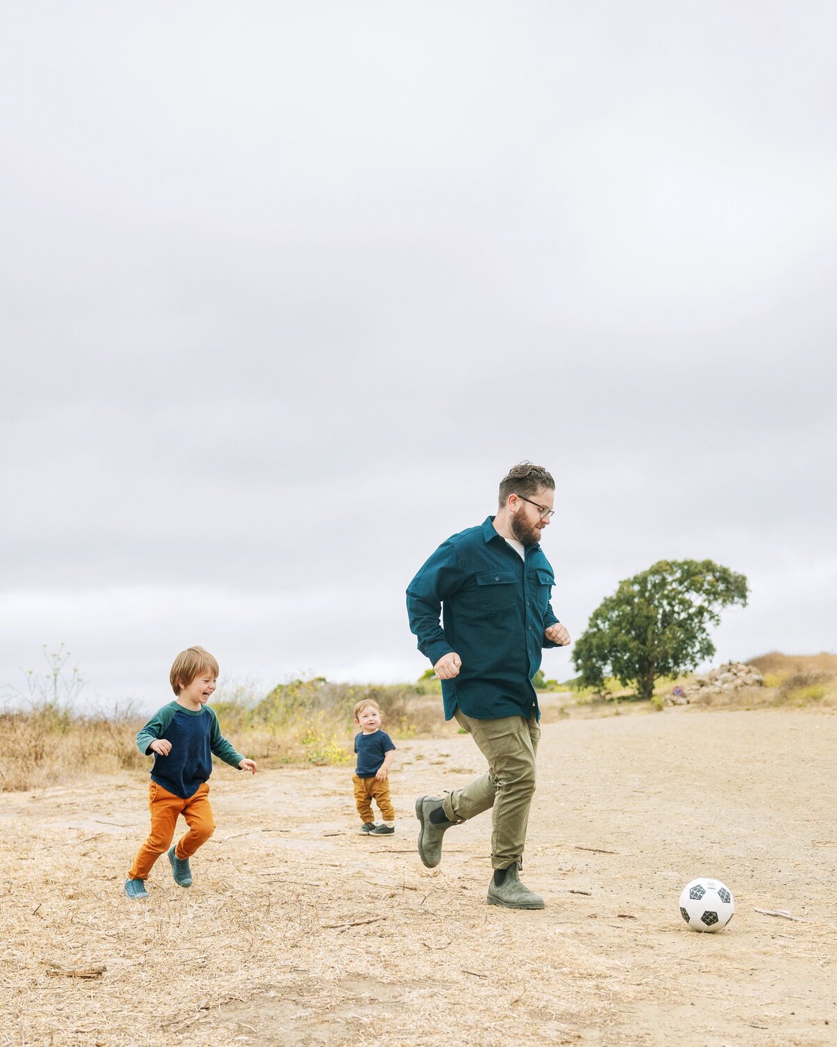 Dad plays soccer with his two kids