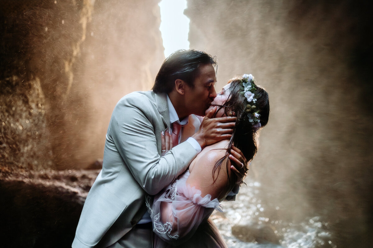young American couple is kissing in a waterfall cave in Iceland