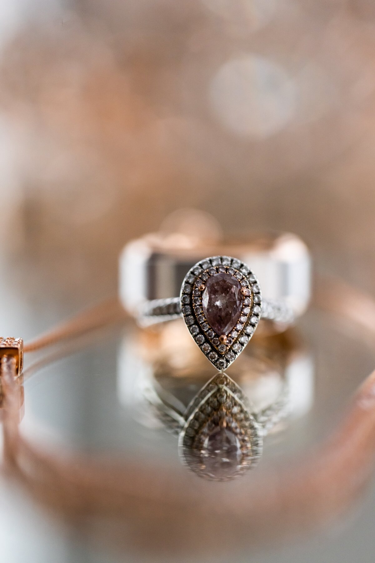 This exquisite macro photograph showcases a wedding ring poised on a reflective surface, capturing the profound elegance and timeless beauty of the symbol. The close-up detail reveals the intricate design and the sparkling brilliance of the diamonds, emphasized by the mirror-like reflection that doubles the visual impact. Ideal for jewelers showcasing their craftsmanship or couples looking for wedding inspiration, this image embodies love's eternal glow and the meticulous attention to detail that goes into every aspect of a wedding.