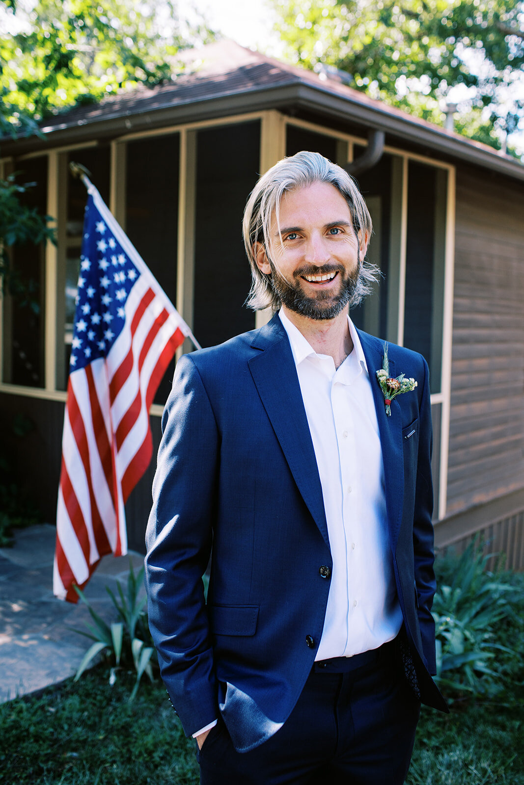 Boulder Colorado groom stands in front of American flag at a Chautauqua cottage