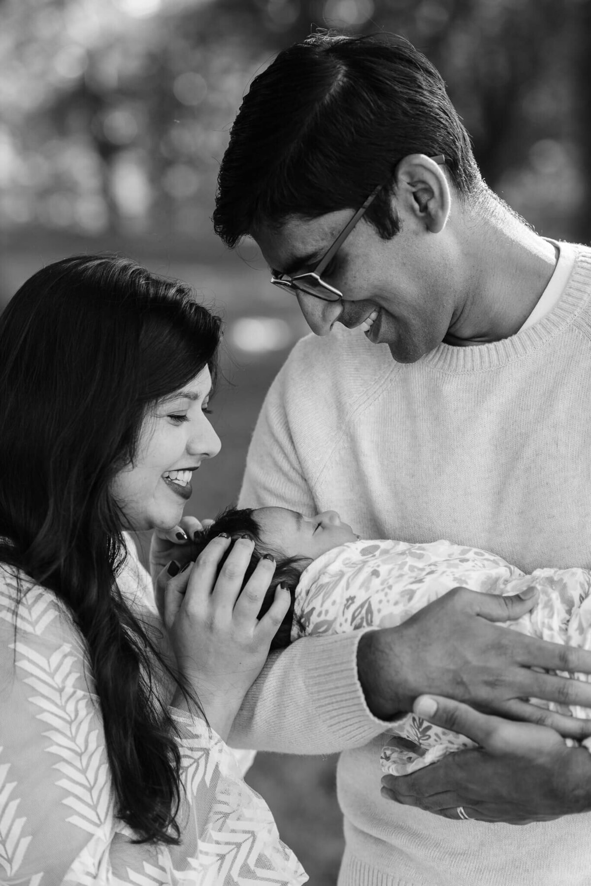 outdoor b&w photography of indian parents smiling at their sleeping daughter, captured in northern VA