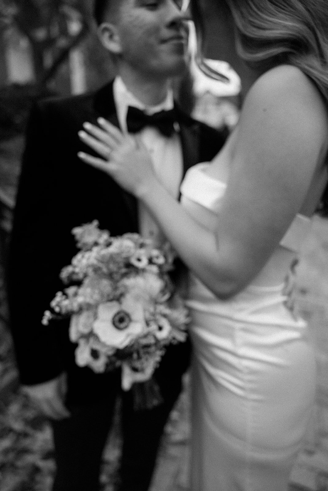A bride in white places her hand on her groom's black tux romantically. 