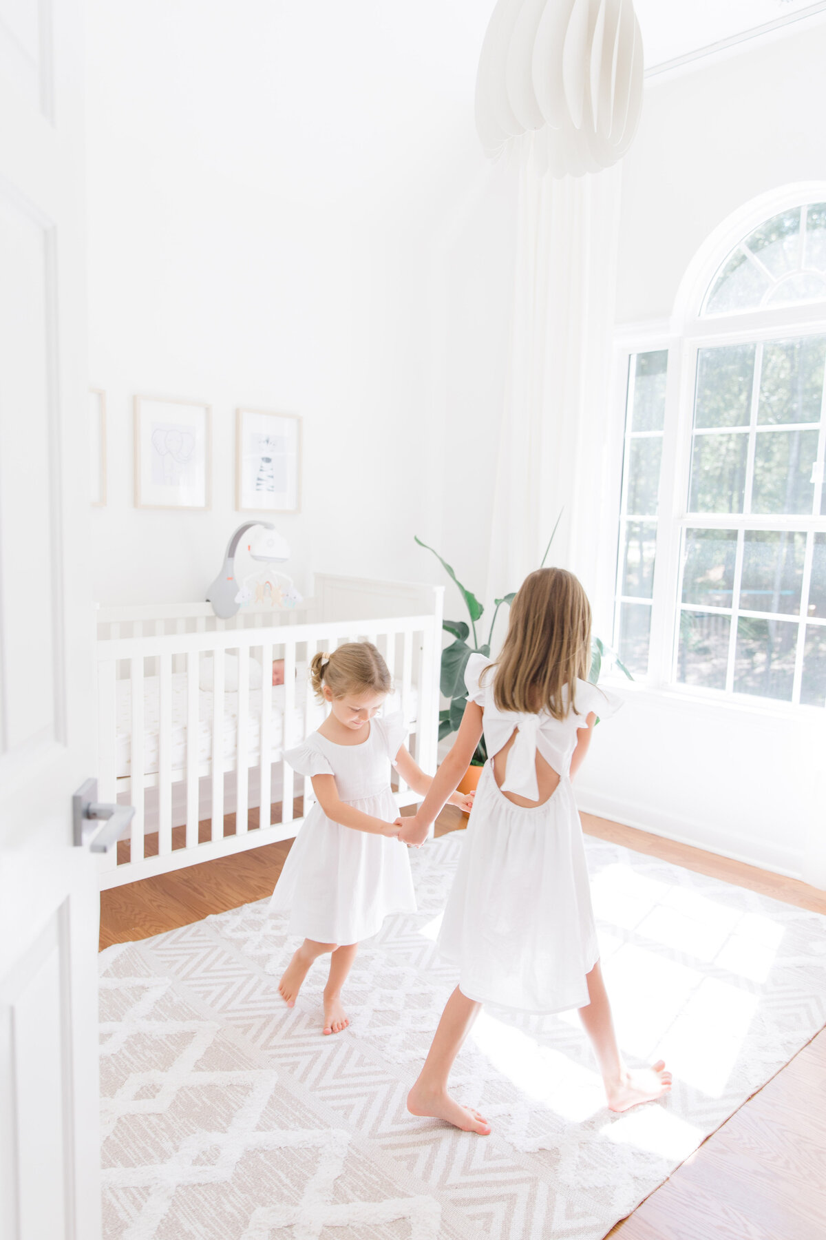 sisters dancing in nursery during in-home newborn session in Charlotte NC