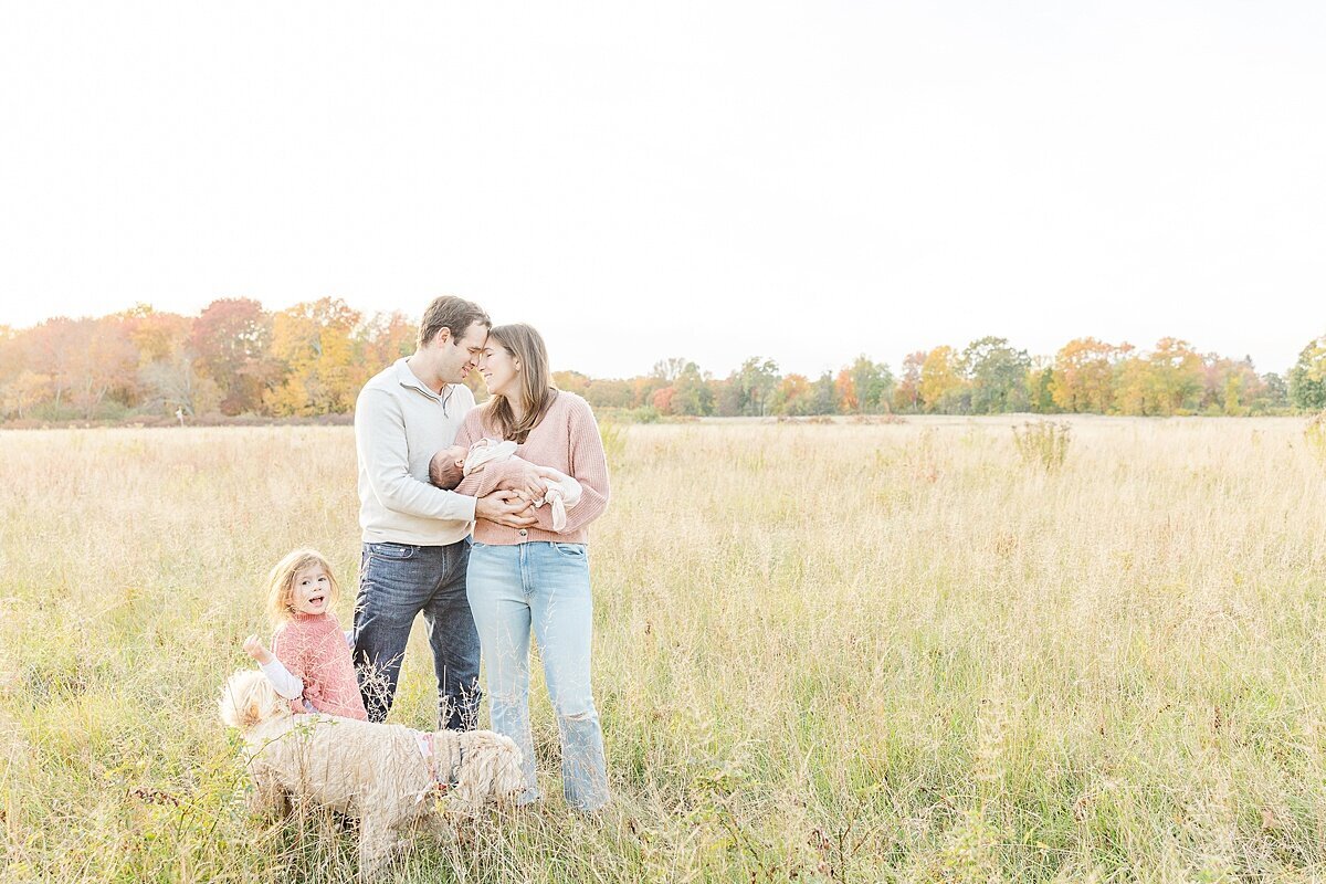 family in field during outdoor newborn photo session with Sara Sniderman Photography