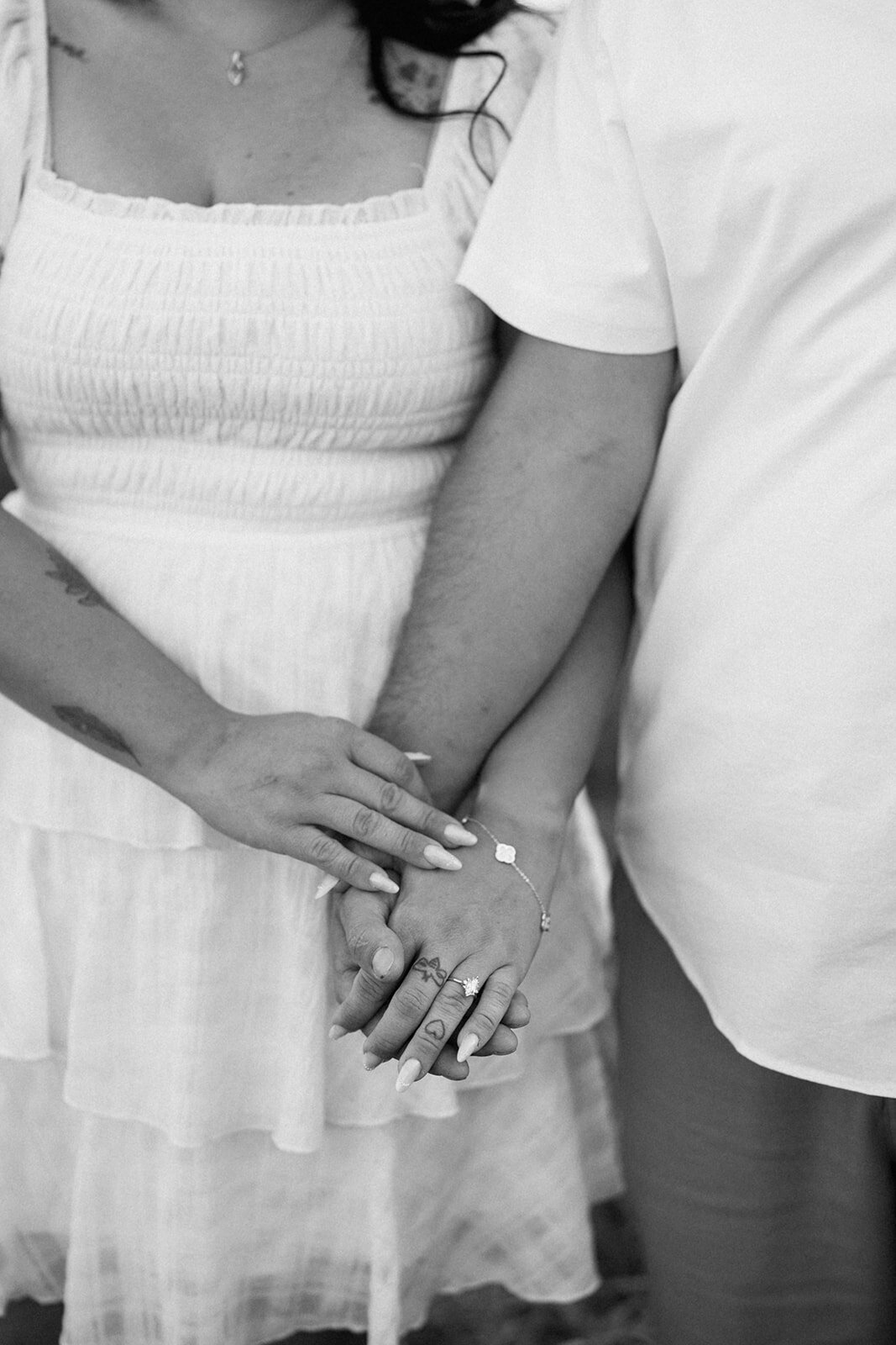 Close-up of Kali and Joe holding hands, showing her engagement ring during their Detroit field engagement session.