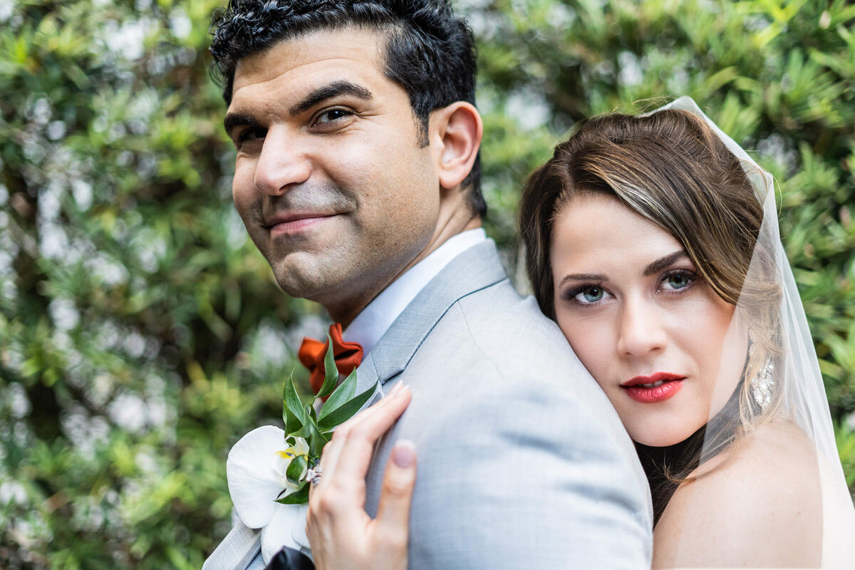 Close-up photo of a bride hugging the groom and looking at the camera, captured as part of their Miami wedding day photo timeline.