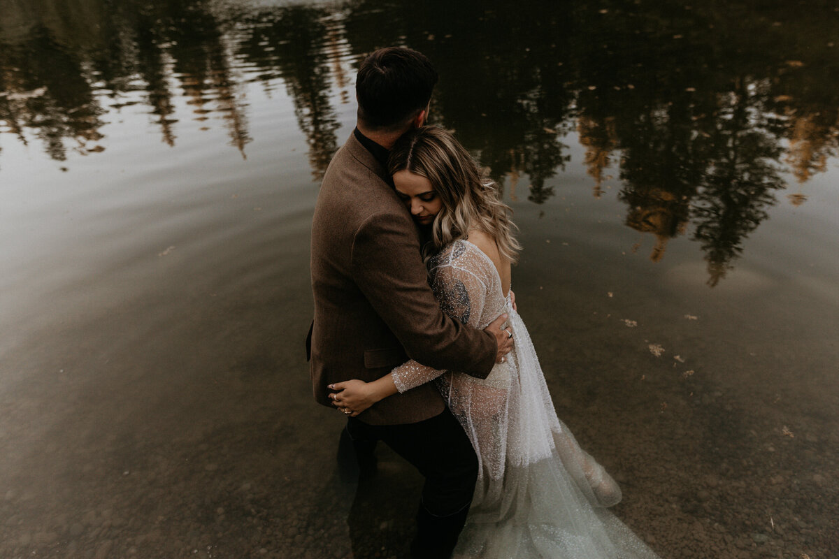 bride and groom together in a pond in their wedding attire