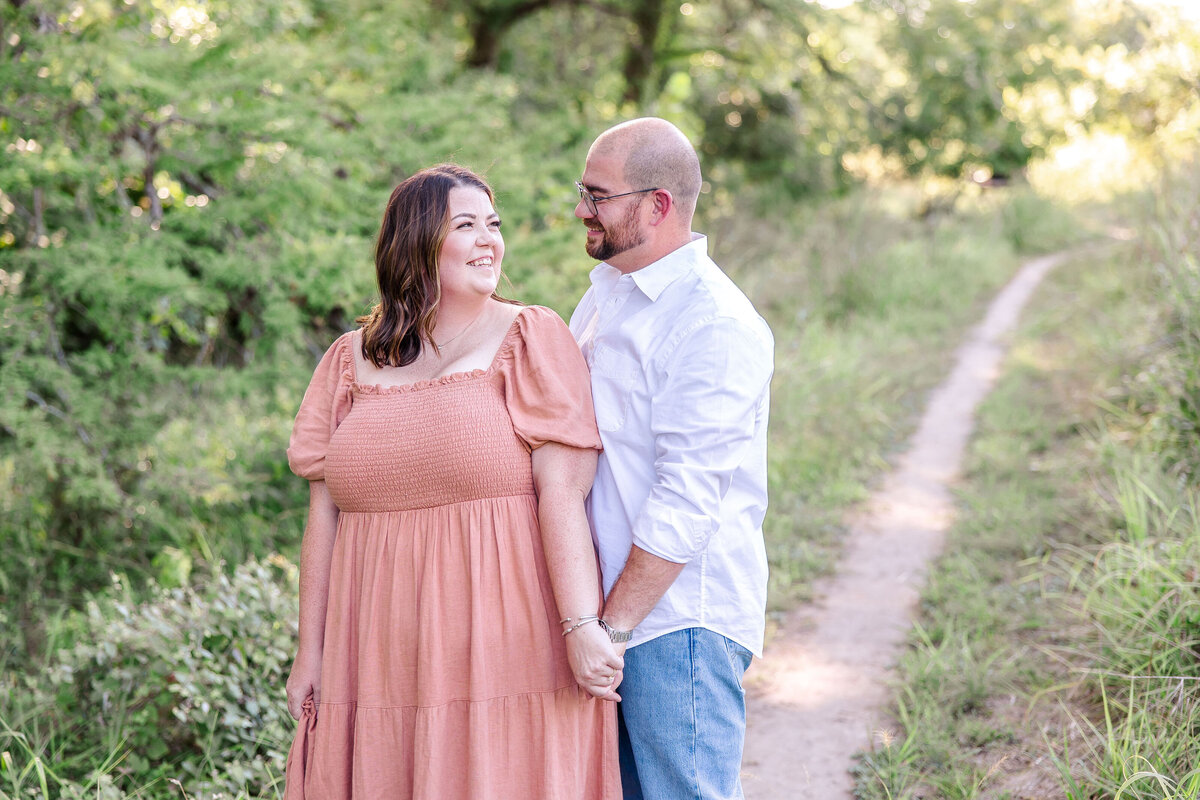 light and airy dressed couple holds hand on path in Boerne Texas before wedding by Firefly Photography