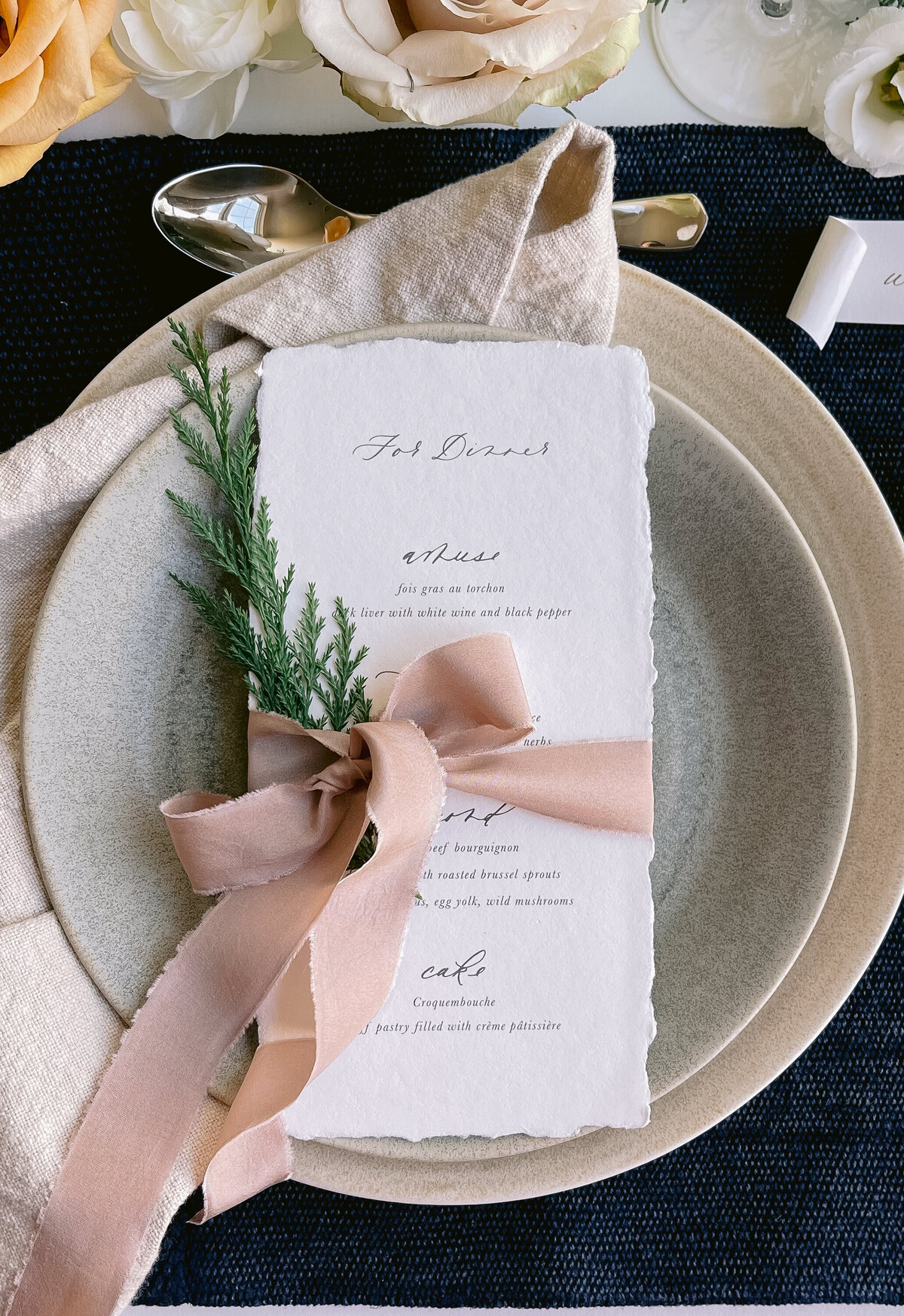 Handmade paper menu with custom calligraphy and a silk ribbon