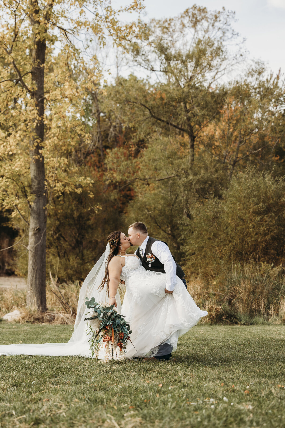 groom-dipping-bride-in-front-of-trees