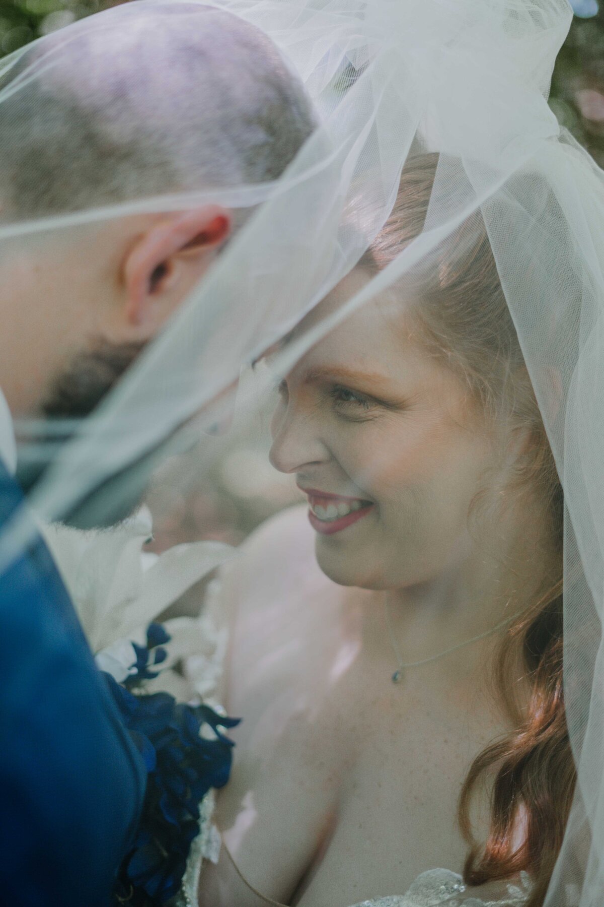 a bride and groom underneath a veil together