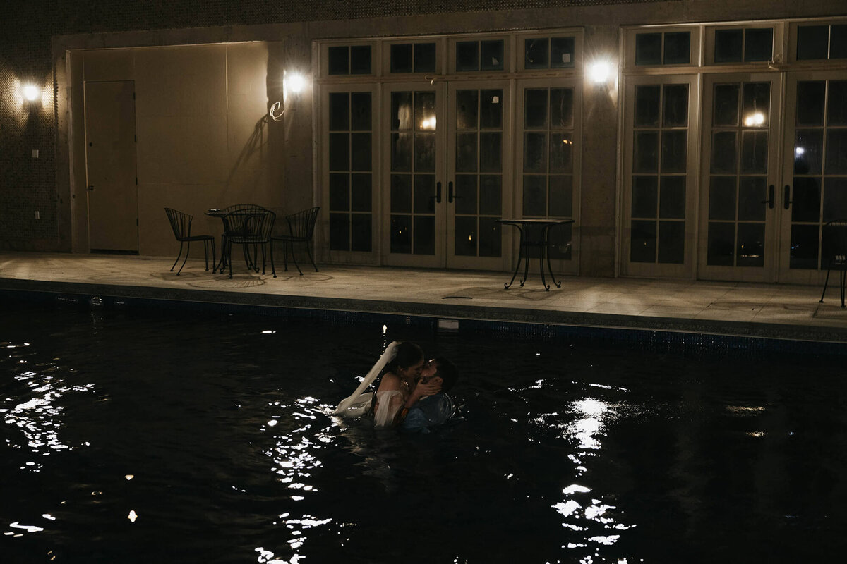 A bride and groom and embrace and kiss after jumping in the outdoor pool at the Chateau de Lis wedding venue.