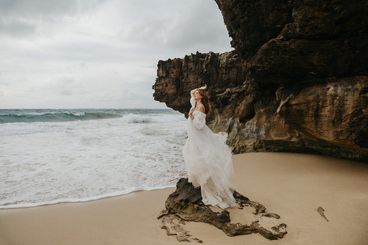 bride standing on rock next to the ocean