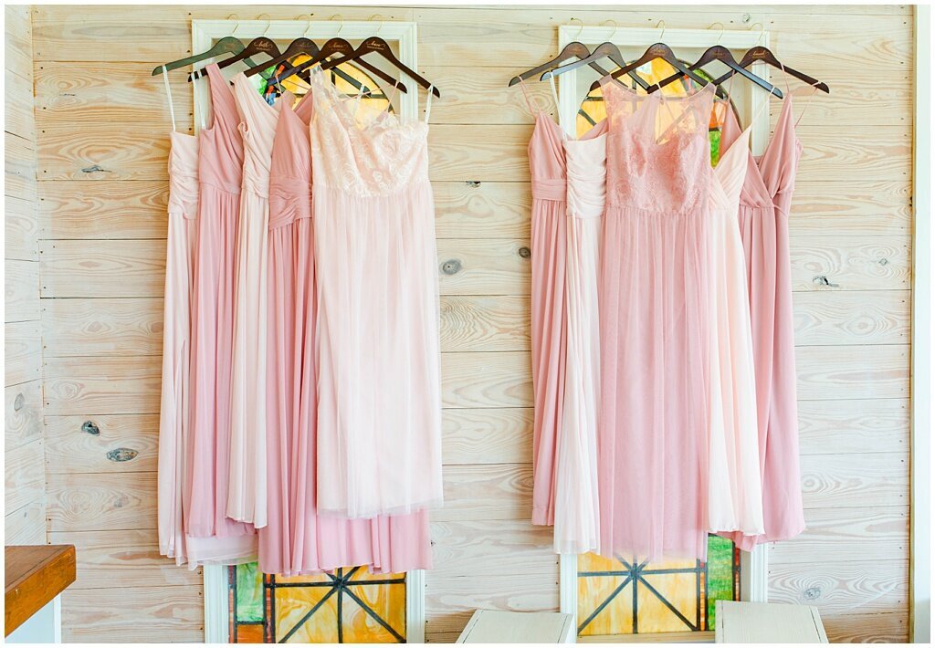 pink bridesmaids dresses hanging against wooden wall