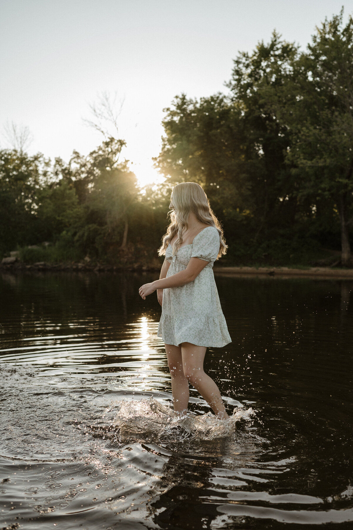 Girl splashing in water at sunset