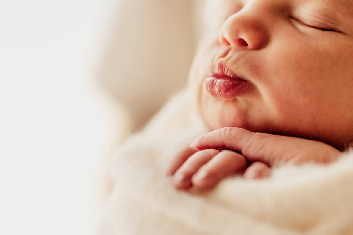 Newborn baby girl puckers her lips.