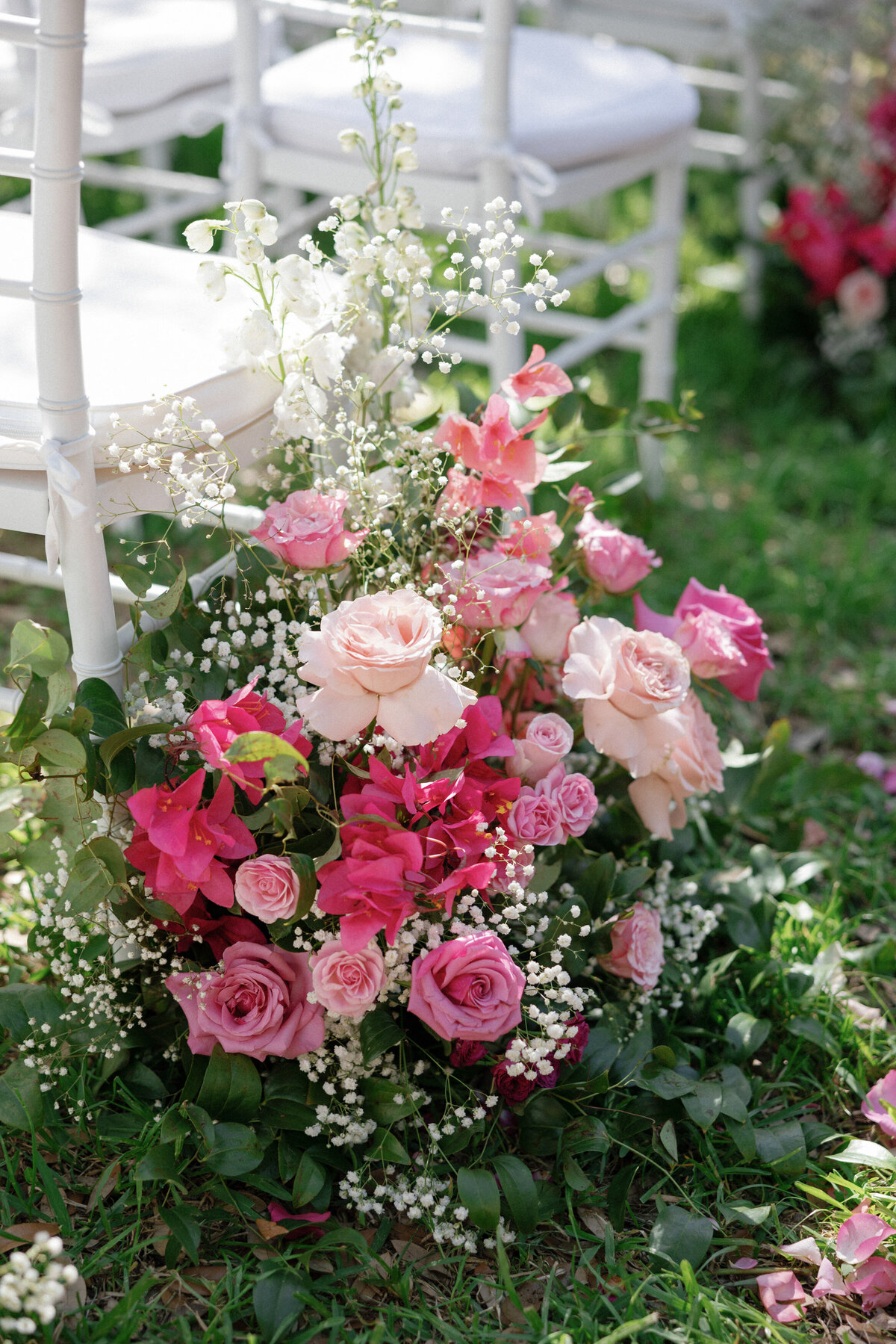 pink florals by white chairs at wedding ceremony