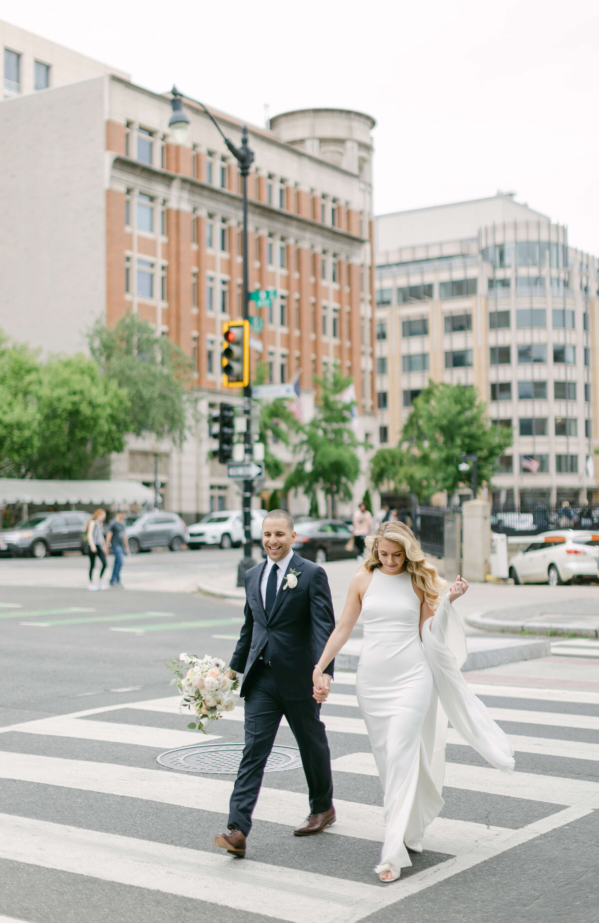 A bride and groom walk across the street of DC.