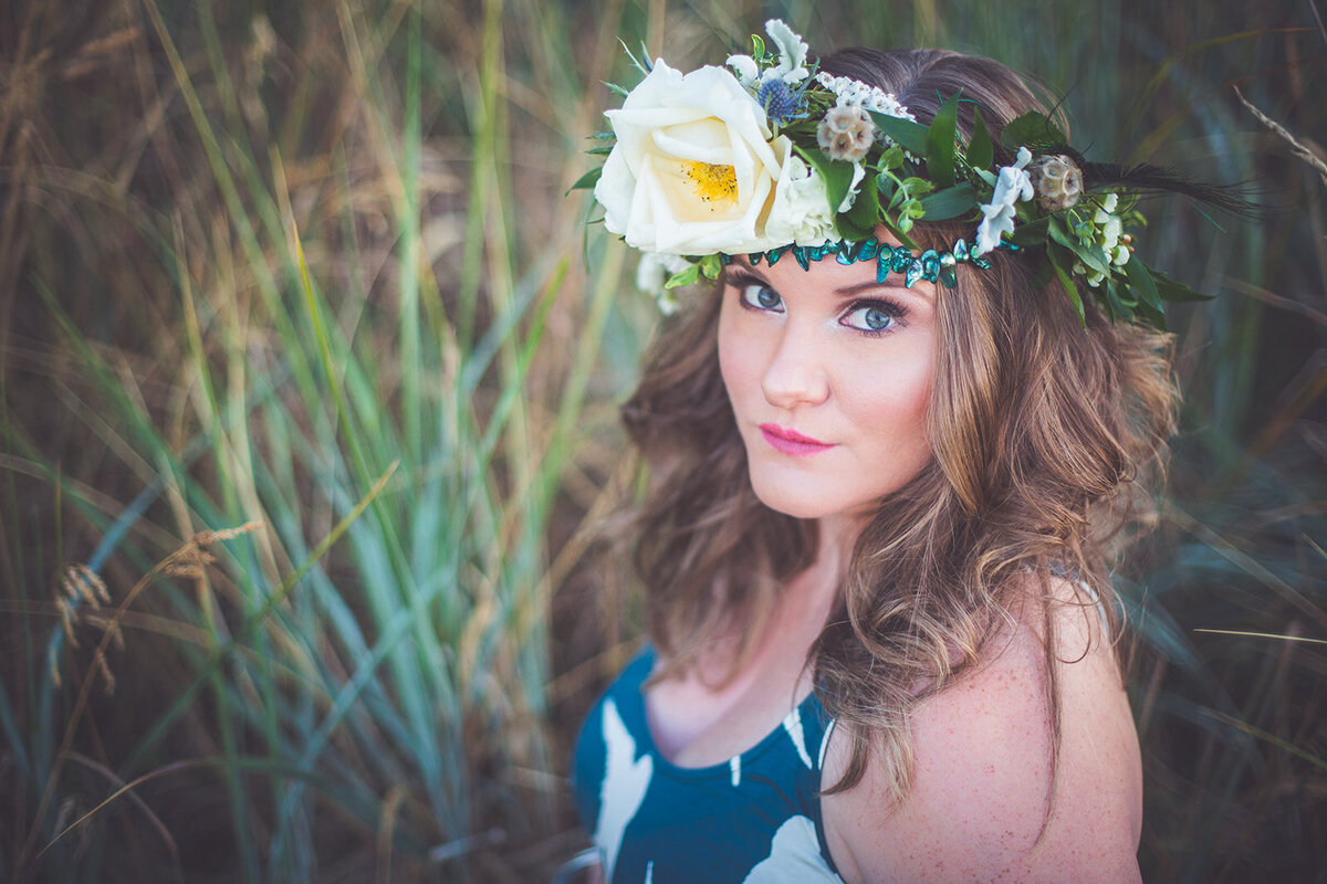 A mom to be with a flower crown in the grass.