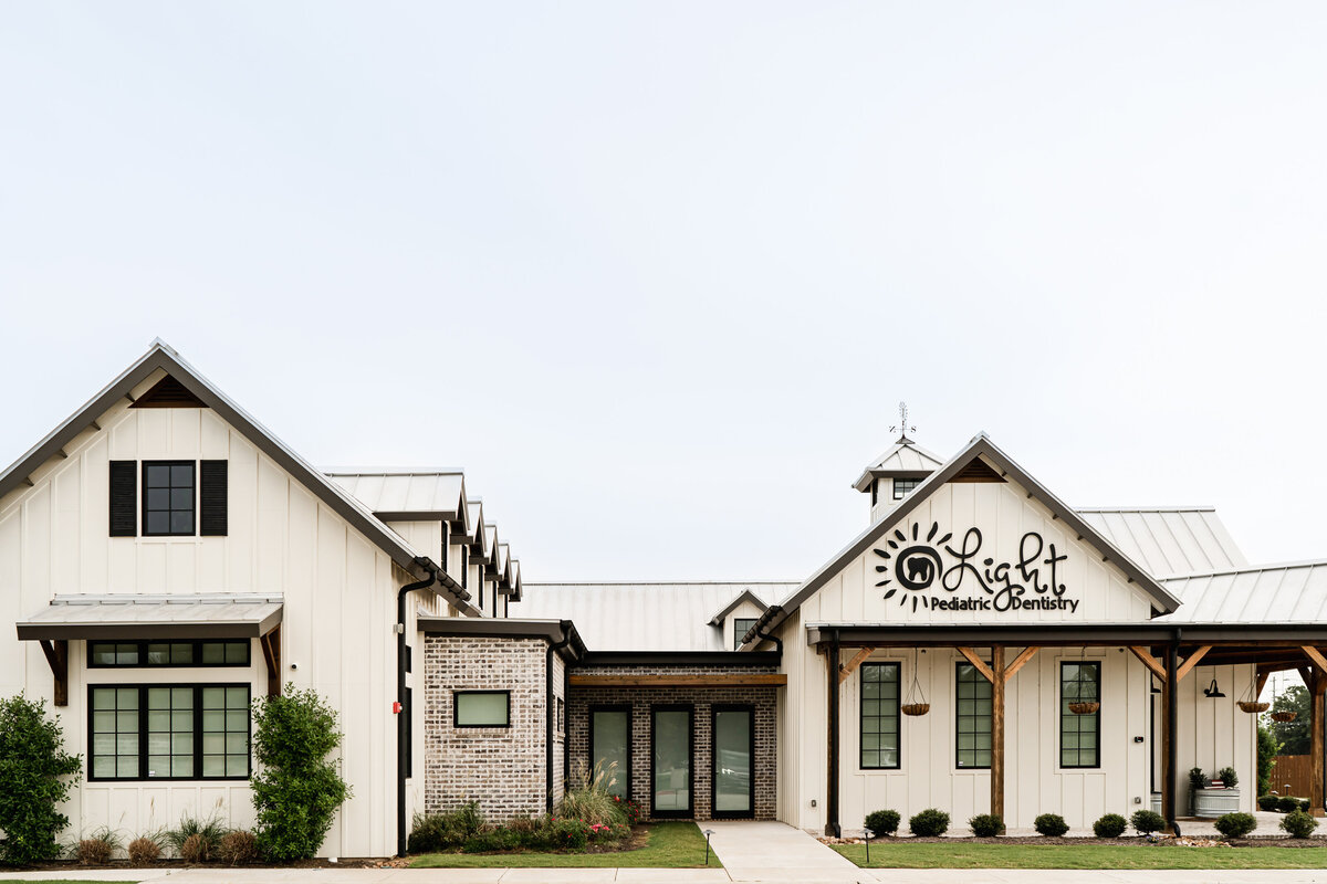 white board and batten with black windows, shutters, standing seam roof and brick accents