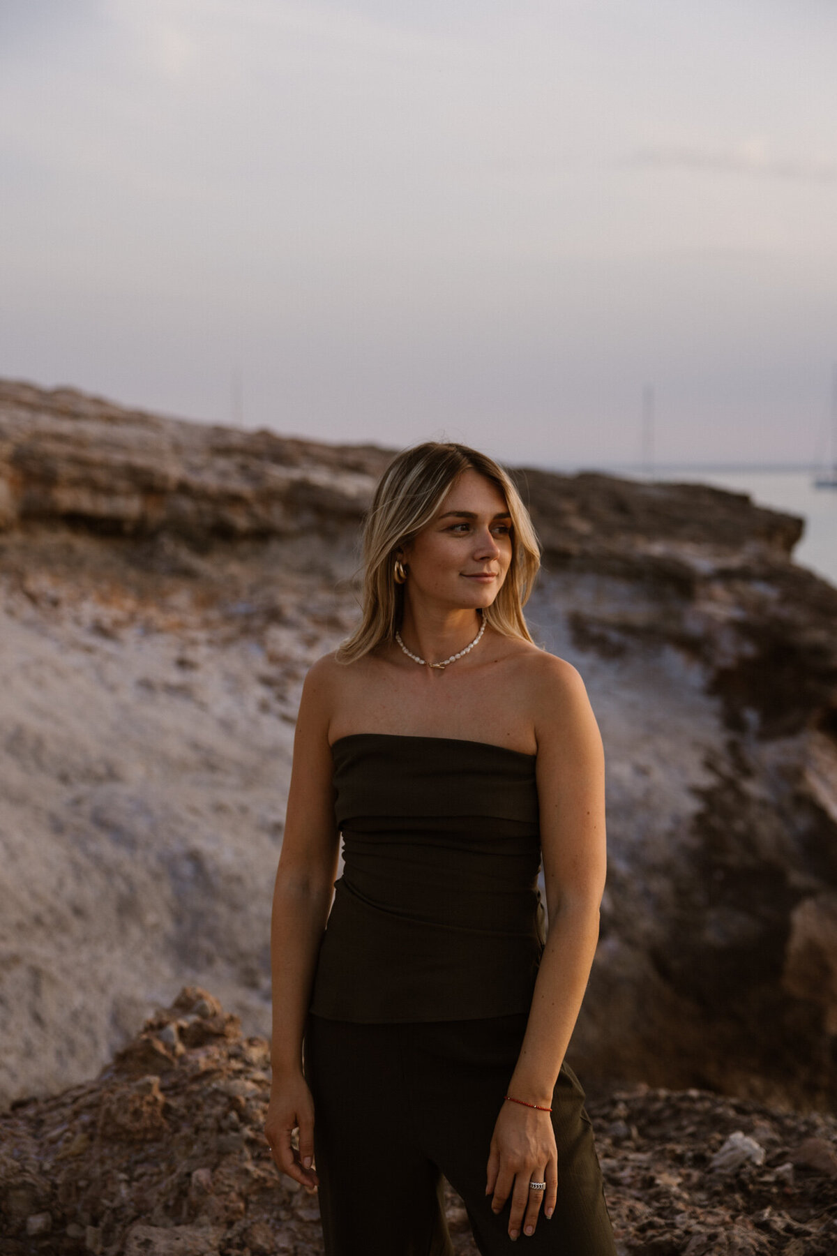 A woman is posing during sunset for her personal branding photography on Ibiza