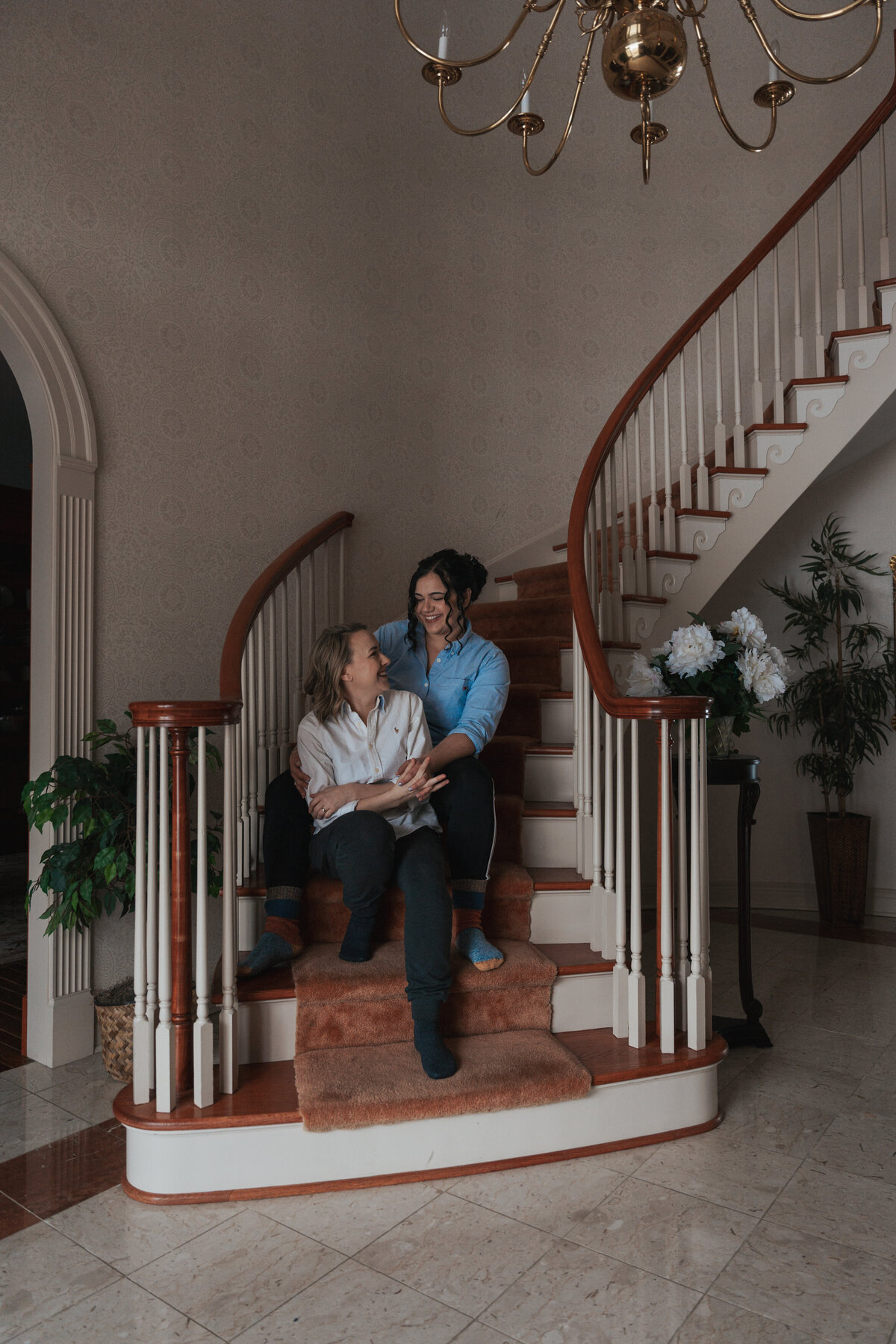 Two newlyweds sit and embrace on a twirly staircase