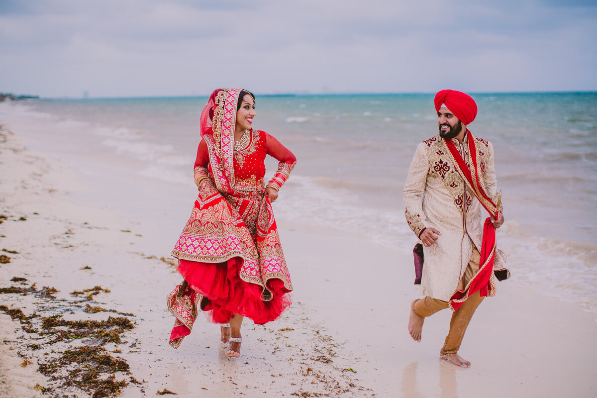 sikh bride and groom running along the beach on their wedding day at moon palace cancun in mexico