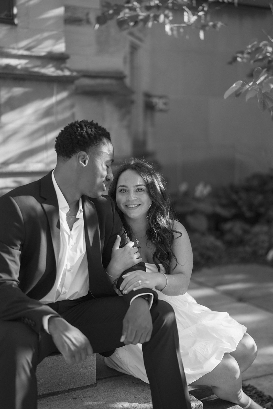 Natural, candid Kalamazoo engagement photo of couple laughing together on stone steps.