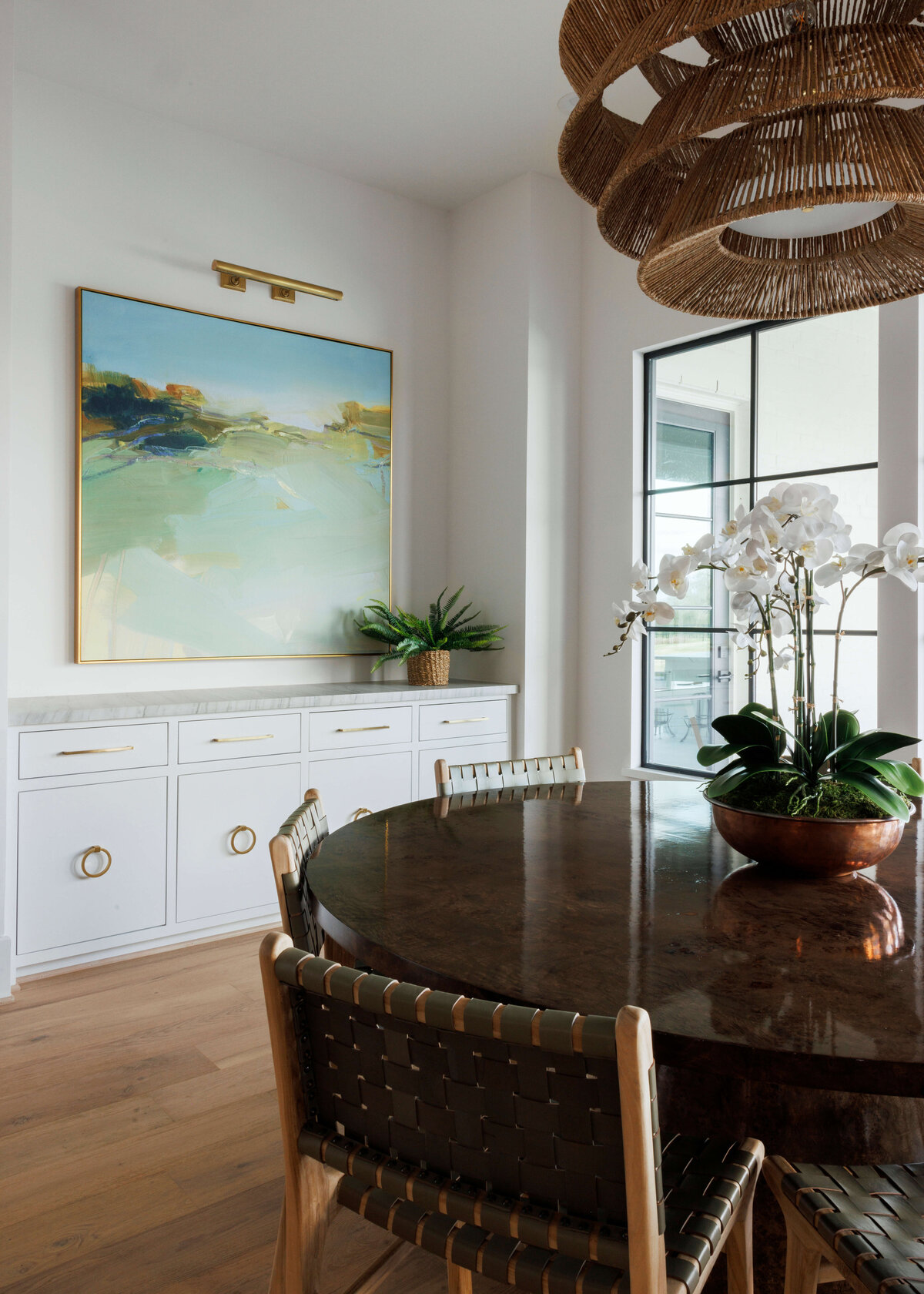 oyster creek studios missouri city new build abstract art and white built in shelving wicker lamp and woven chairs around a dining room table