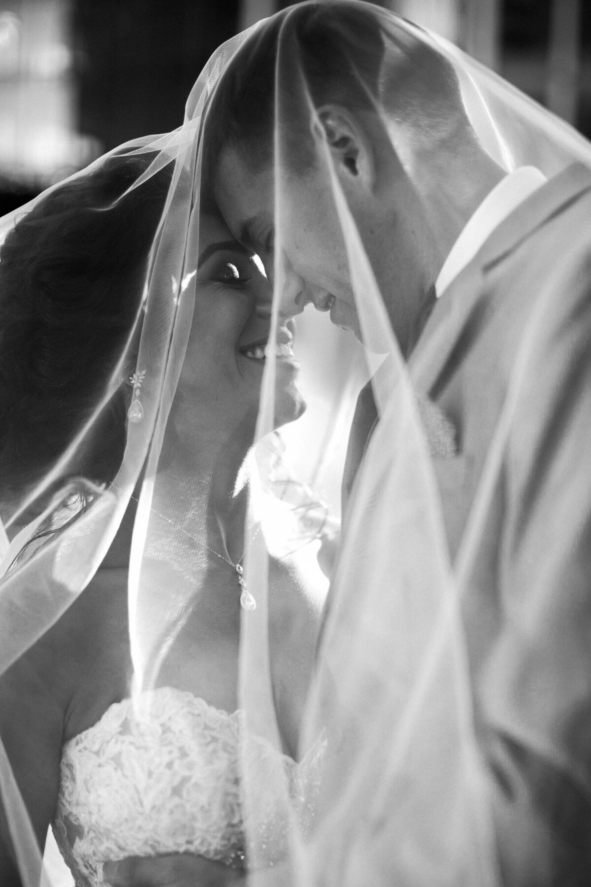 Black-and-white-photo-of-bride-and-groom-cuddling-under-a-veil-at-Seattle-wedding-photo-by-Joanna-Monger-Photography