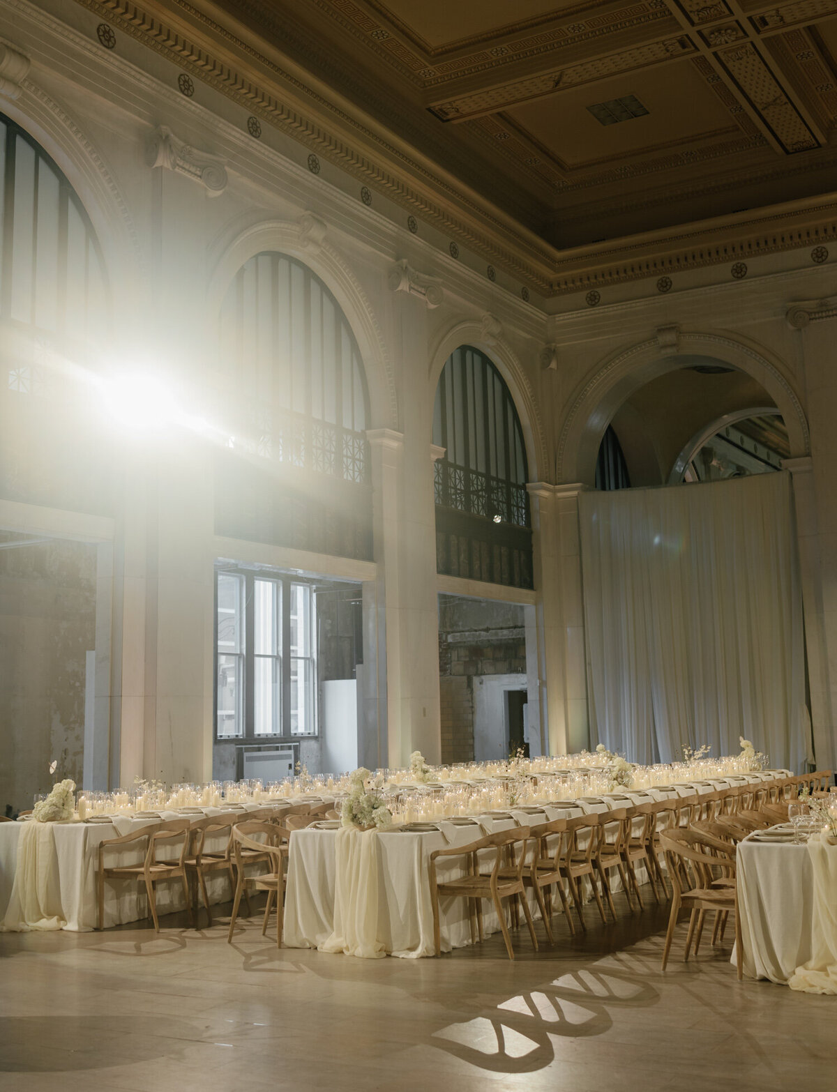 Soft light pours over tables with hundreds of candles for a State Savings Bank wedding reception in Detroit