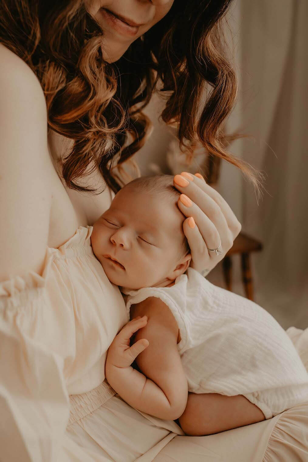 A new mother holds her sleeping newborn girl against her chest while cradling her head