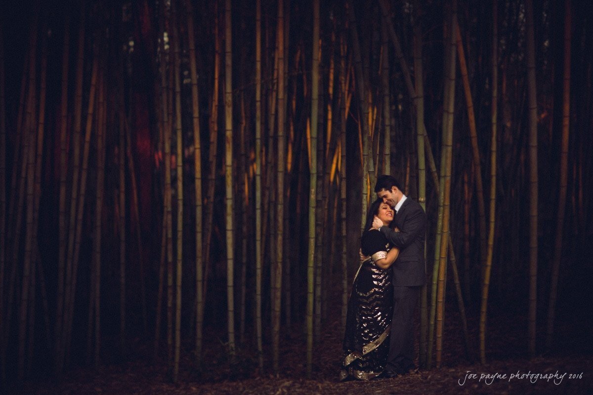 A couple hugging each other against bamboo trees.