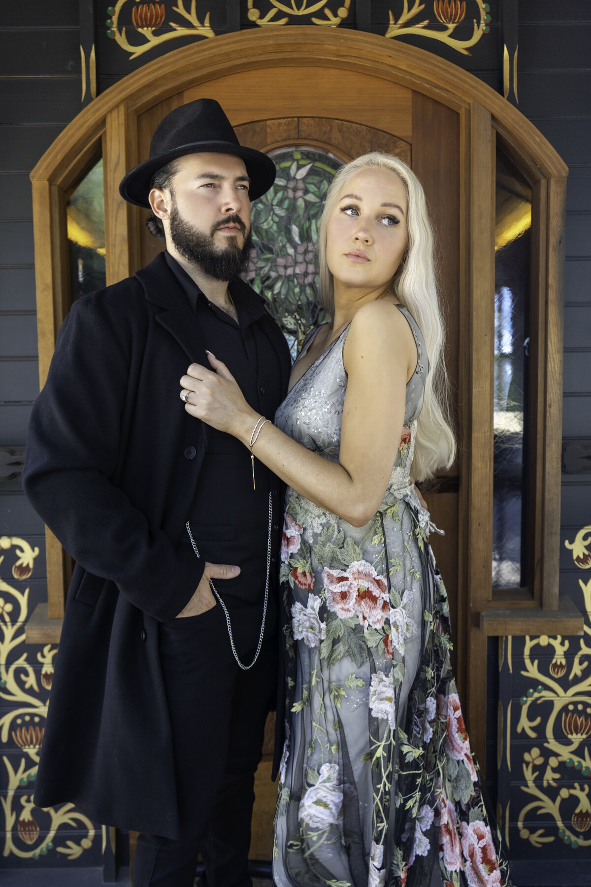 Closeup portrait of engaged couple in Malibu mountains with the man in Peaky Blinders inspired outfit and the woman in colored lace Claire Pettibone gown
