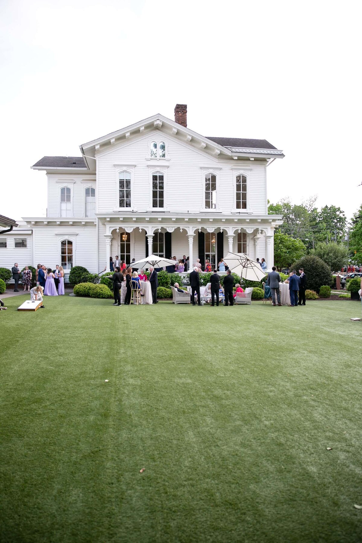 Wedding party and wedding guests celebrating in front of the Merrimon-Wynne House’s historic white façade