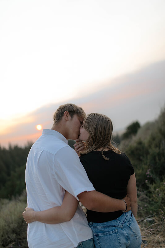 A man kisses his girlfriend. They're facing away from the camera so you can't really see their faces.
