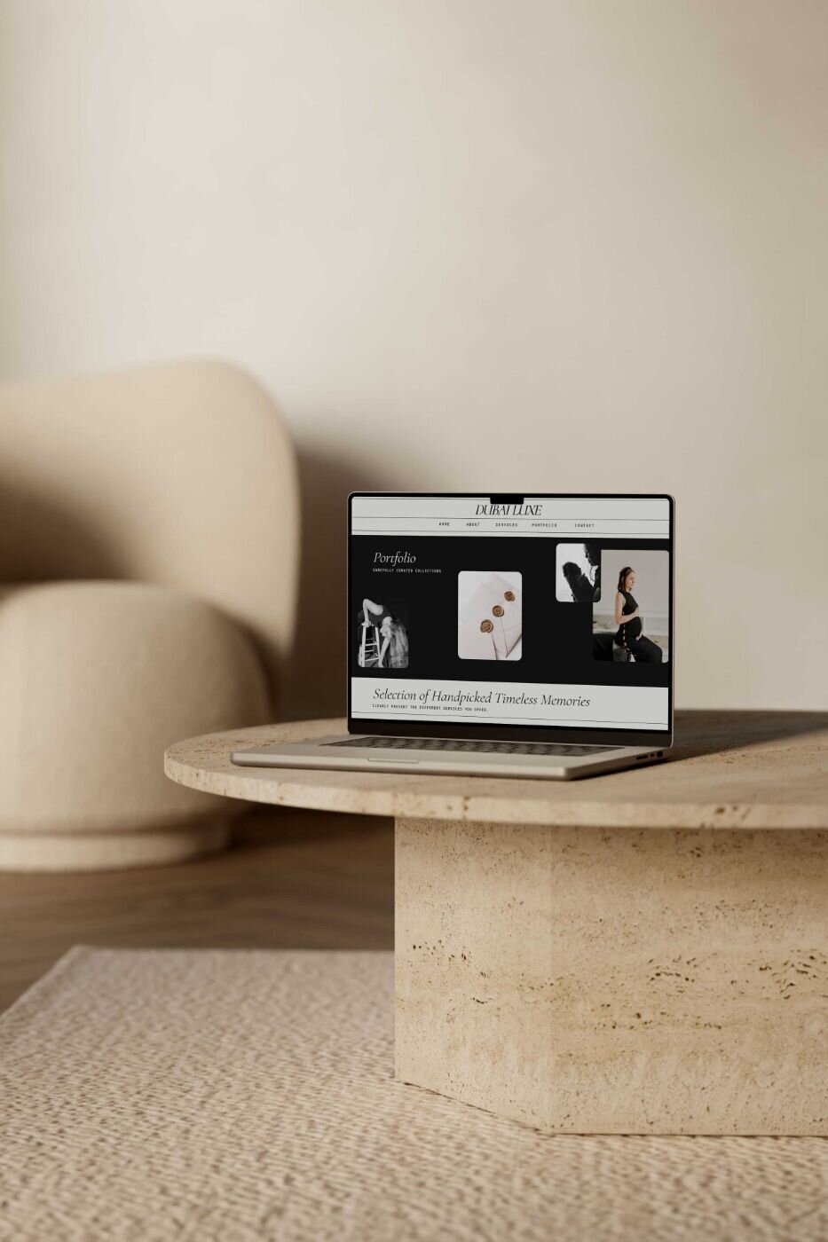 Laptop placed on a round stone coffee table in a minimalist beige room, displaying the “Dubai Luxe” photography portfolio page featuring black-and-white and color portraits of women and fine-art details.