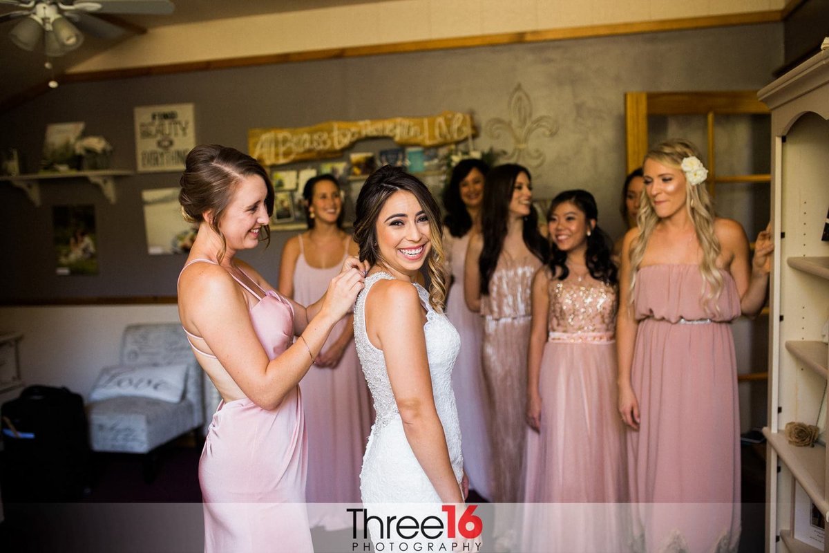 Bridesmaids surround the Bride as the final button is fastened