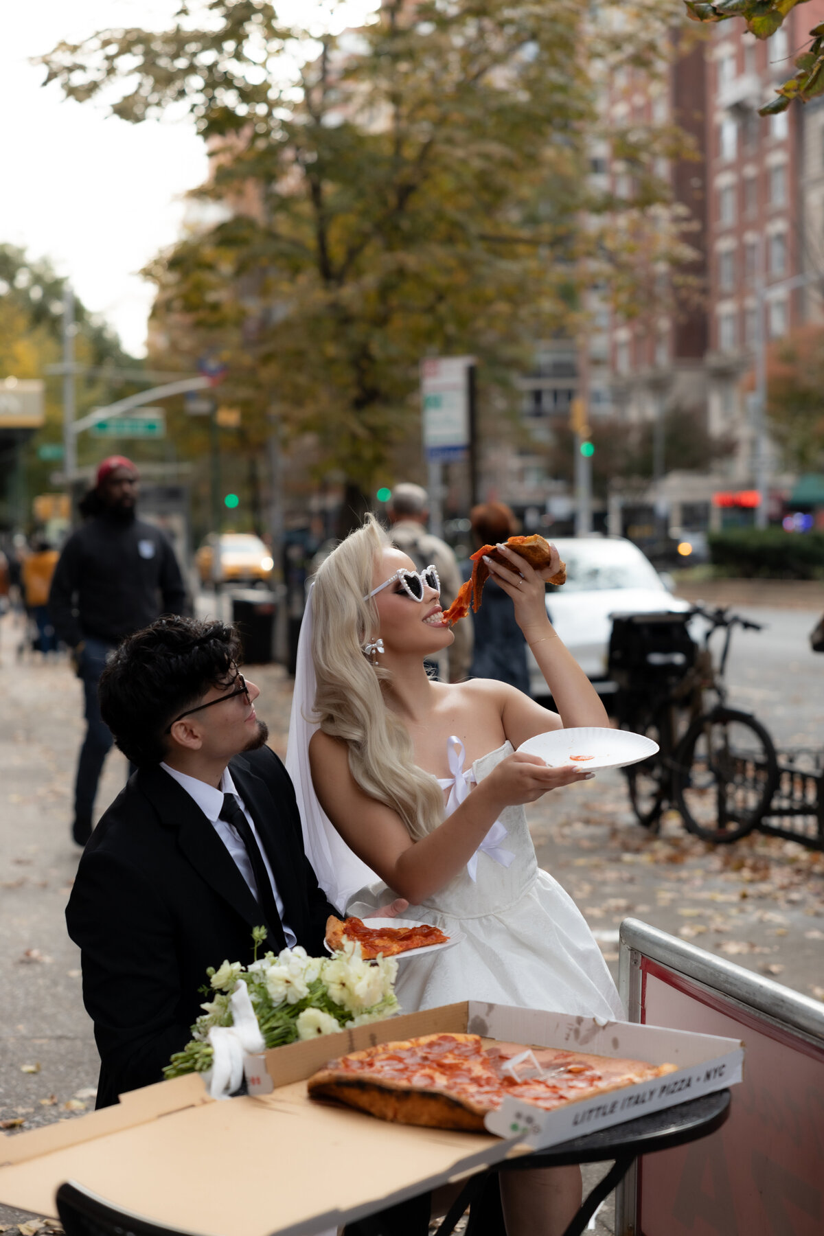 Bride and groom sharing a romantic moment while splitting a slice of pizza in NYC.
